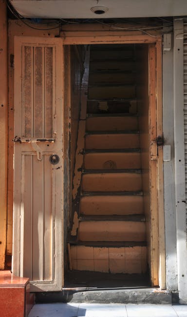 Inside a residential property during a home relocation, several large cardboard boxes filled with fragile items are stacked carefully on the floor near a wide doorway. A padded moving blanket covers a